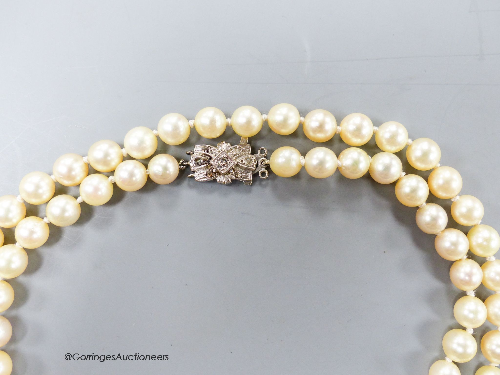 A single strand cultured pearl necklace, with 18ct white metal and diamond set bow clasp, 72cm, gross 47.6 grams.